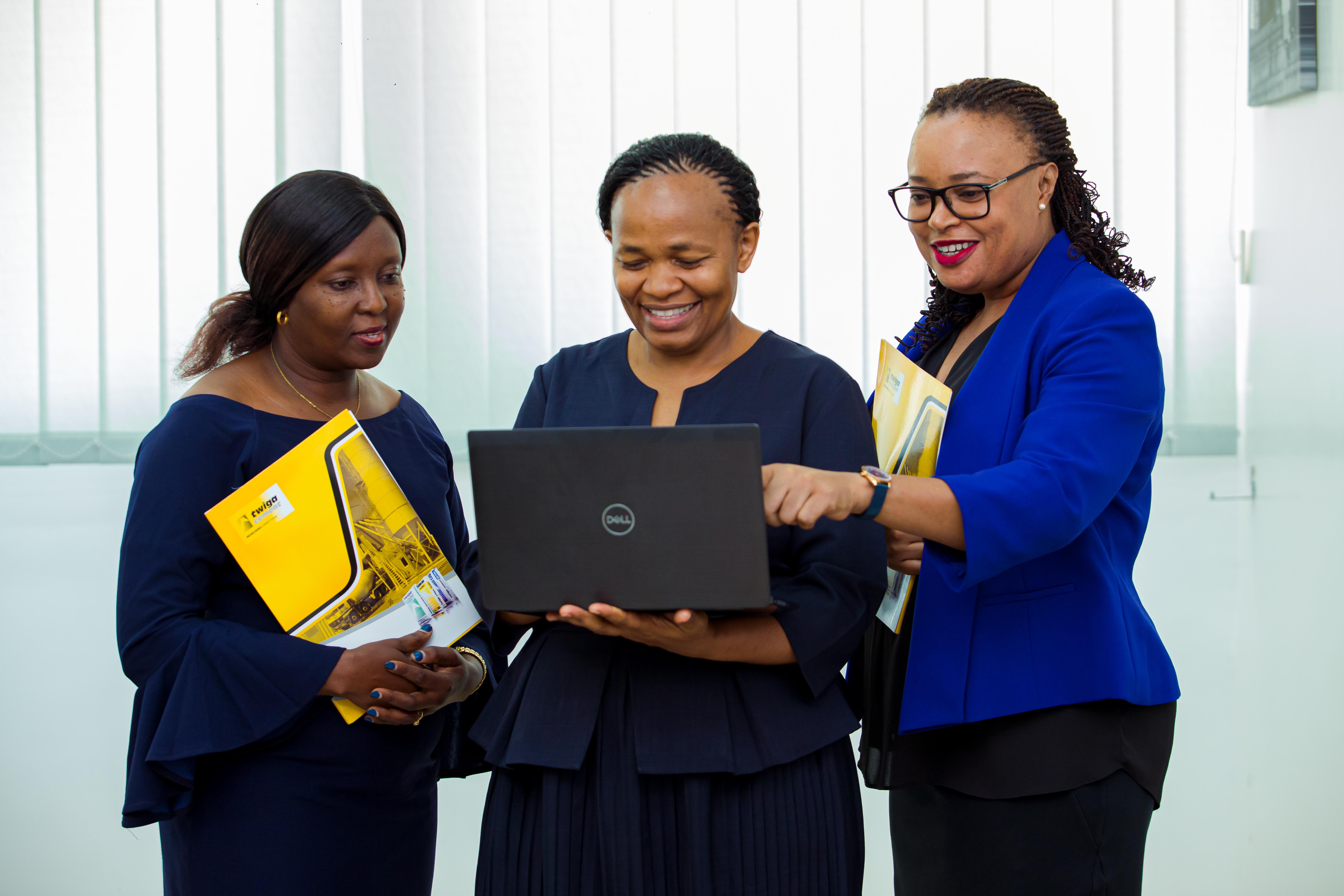 Three women reading on same laptop
